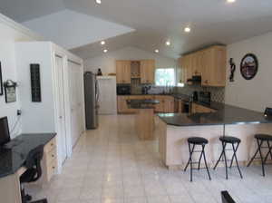 Kitchen featuring light tile patterned floors, sink, black appliances, a kitchen bar, and decorative backsplash