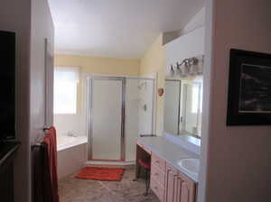 Bathroom featuring vanity, lofted ceiling, and shower with separate bathtub