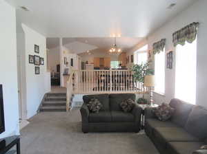 Carpeted living room featuring lofted ceiling and a notable chandelier