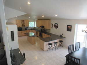 Kitchen featuring stainless steel appliances, sink, lofted ceiling, kitchen peninsula, and tasteful backsplash