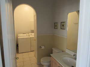 Bathroom with tile patterned flooring, vanity, washer and clothes dryer, and toilet