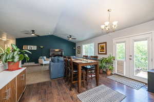 Dining space featuring ceiling fan with notable chandelier, a textured ceiling, lofted ceiling, and dark hardwood / wood-style floors