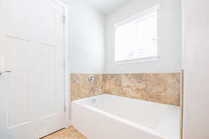 Bathroom with tile patterned flooring, a washtub, and a wealth of natural light