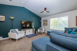 Living room with vaulted ceiling, a textured ceiling, ceiling fan, and carpet