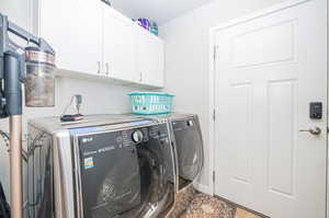 Washroom with cabinets, independent washer and dryer, and a textured ceiling