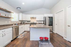 Kitchen with white cabinets, appliances with stainless steel finishes, dark hardwood / wood-style flooring, and vaulted ceiling