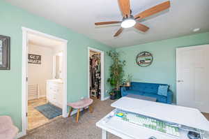 Bedroom with ensuite bath, a spacious closet, carpet, ceiling fan, and a textured ceiling