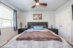 Bedroom with a closet, ceiling fan, and a textured ceiling