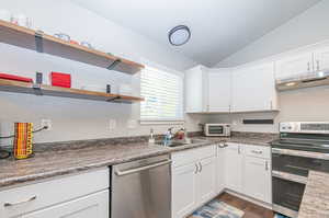 Kitchen with lofted ceiling, dark hardwood / wood-style flooring, stainless steel appliances, and white cabinetry