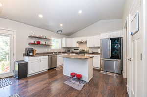 Kitchen with lofted ceiling, plenty of natural light, dark wood-type flooring, and stainless steel appliances