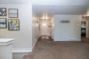 Entryway featuring a textured ceiling and dark colored carpet