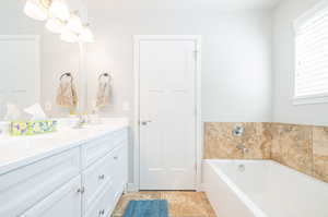 Bathroom with a bathtub, a healthy amount of sunlight, vanity, and tile patterned flooring