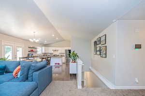 Living room featuring vaulted ceiling, a textured ceiling, wood-type flooring, and a notable chandelier