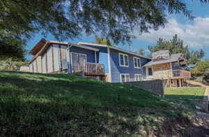 Rear view of property with a lawn and a deck