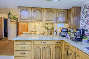 Kitchen with light stone countertops, kitchen peninsula, and a textured ceiling