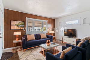 Living room featuring a wealth of natural light, wooden walls, and a textured ceiling