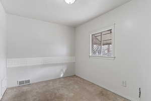 Unfurnished room featuring a textured ceiling and light colored carpet