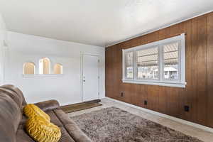 Carpeted living room with a textured ceiling and wooden walls