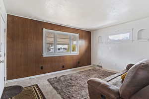 Living area with a textured ceiling, plenty of natural light, and wooden walls