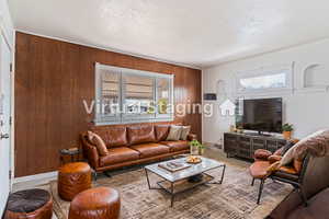 Living room with a textured ceiling, a wealth of natural light, and wood walls