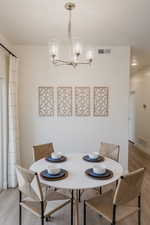 Dining area with a notable chandelier and wood-type flooring