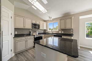 Kitchen featuring a center island, tasteful backsplash, stainless steel appliances, and dark stone counters