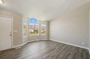 Entryway featuring dark wood-type flooring, a textured ceiling, and lofted ceiling