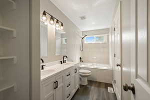 Full bathroom featuring vanity, tiled shower / bath, toilet, and hardwood / wood-style flooring