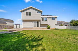 Back of property with a mountain view, a yard, and a patio