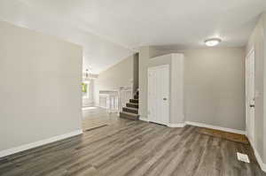 Spare room featuring hardwood / wood-style floors, a notable chandelier, and vaulted ceiling