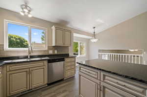 Kitchen featuring dishwasher, pendant lighting, cream cabinets, dark wood-type flooring, and sink