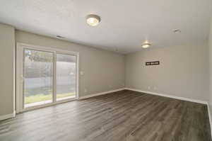 Empty room featuring dark wood-type flooring and a textured ceiling