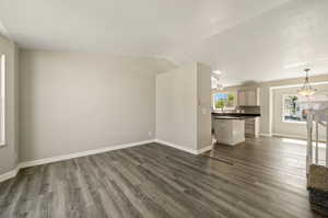 Unfurnished living room with dark wood-type flooring, lofted ceiling, and a textured ceiling