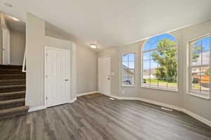 Entrance foyer with vaulted ceiling, a textured ceiling, and hardwood / wood-style floors