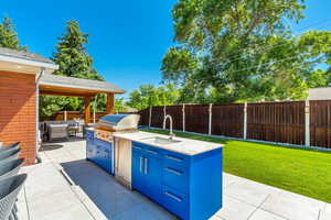 Outdoor kitchen includes a 44" built-in infrared grill, 24" refrigerator that can hold 152 cans, and fully plumbed quartz sink (hot and cold water and garbage disposal that drains out to city sewer). The countertop is Dekton - a porcelain ultracompact mat