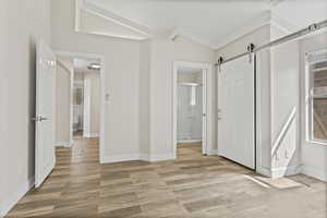 Master bedroom with a barn door, and vaulted ceiling