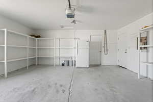 Garage with a garage door opener and white fridge