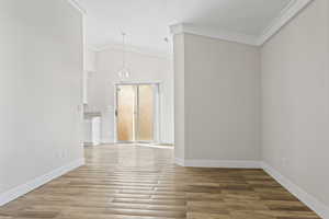 Living room featuring an inviting chandelier, crown molding, vaulted ceiling, and LVP floors