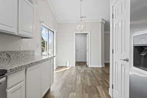 Kitchen featuring a chandelier, white cabinets, decorative light fixtures, and ornamental molding