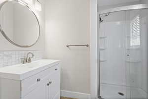 Master bathroom featuring vanity, backsplash, and a shower with shower door