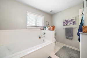 Bathroom with a bath, toilet, and a textured ceiling