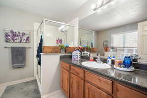 Bathroom featuring a shower with door, vanity, and a textured ceiling