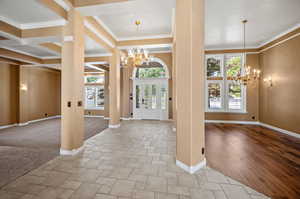 Foyer with light wood-type flooring, beamed ceiling, a notable chandelier, and ornamental molding