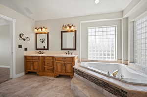 Master Bathroom featuring a relaxing tiled tub and vanity