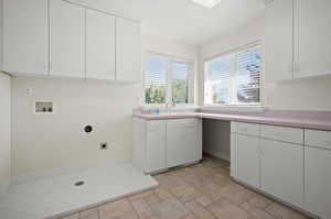 Clothes washing area with hookup for a washing machine, cabinets, sink, and hookup for an electric dryer