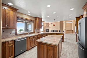 Kitchen featuring a textured ceiling, a kitchen island, pendant lighting, appliances with stainless steel finishes, and sink