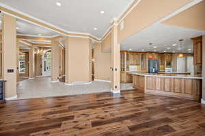 Kitchen featuring a notable chandelier, ornamental molding, a spacious island, dark wood-type flooring, and appliances with stainless steel finishes