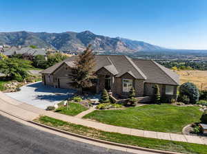 View of front of home with a mountain view, a garage, and a front lawn