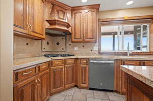 Kitchen featuring appliances with stainless steel finishes, tasteful backsplash, sink, and light stone countertops