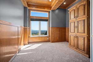 Large Home Office with wood ceiling, light colored carpet, and wooden walls